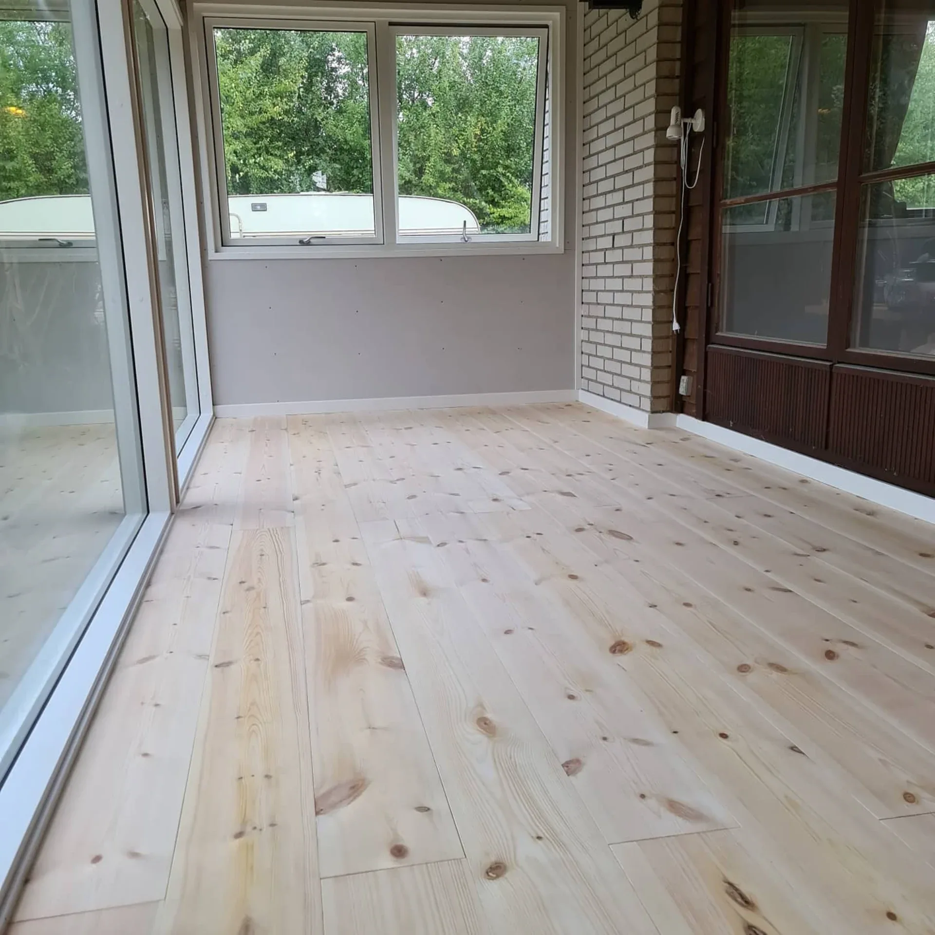 Nyrenoveret træterrasse med store vinduer og udsigt til naturen.
