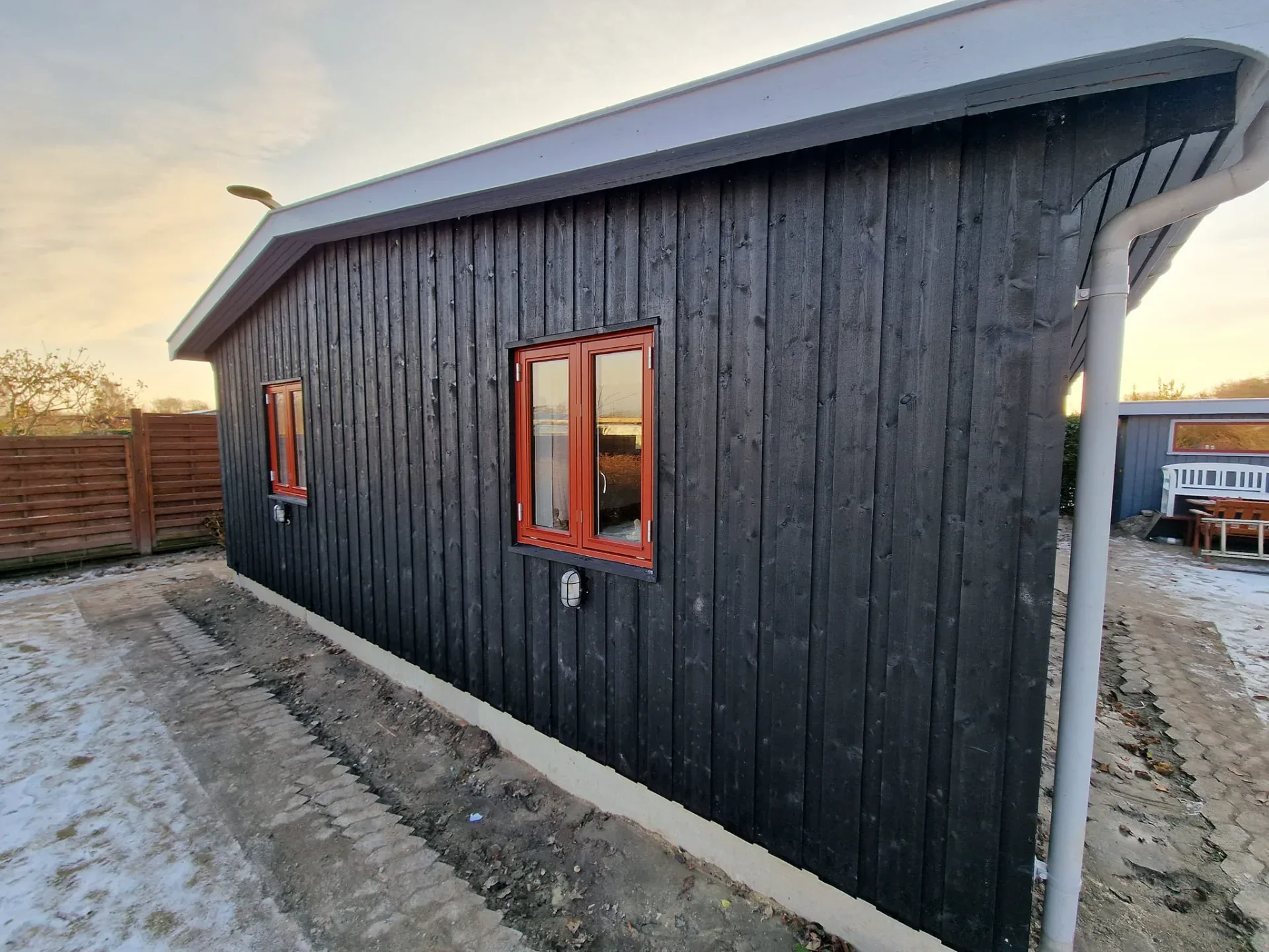 Højkvalitets sort træhus med moderne design og store vinduer, perfekt til bolig eller fritidshus.